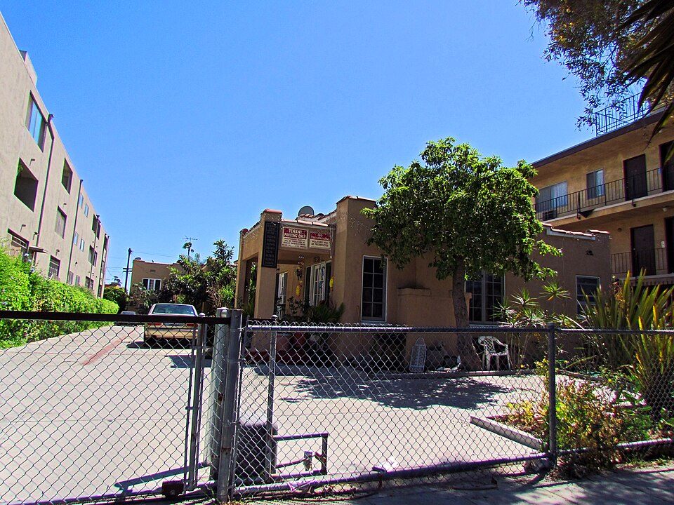 A small stucco bungalow court behind a chain-link fence in East Hollywood