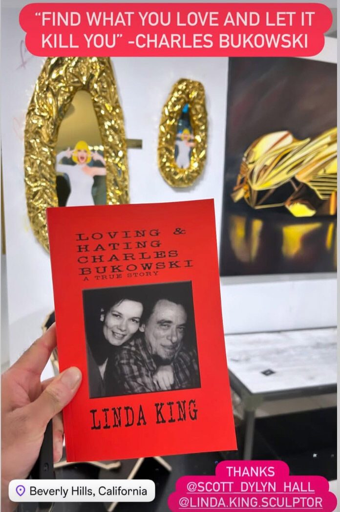 Hand holding a copy of Loving and Hating Charles Bukowski in front of the show